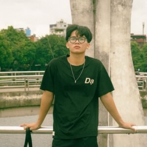 A young man with glasses poses in an urban setting. Ideal for lifestyle themes.