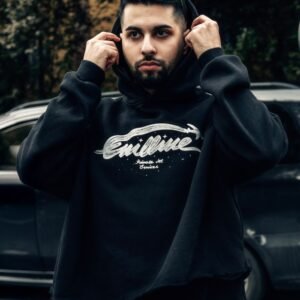 Young man in stylish black hoodie adjusting his glasses outdoors.