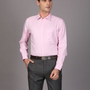 Professional man in pink shirt and gray pants posing confidently in studio setting.
